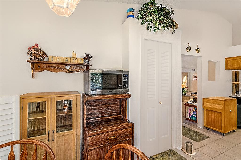 A dining area features a wooden hutch, a microwave, and a white louvered closet door — 1237 FRANFORD DRIVE, BRANDON, FL