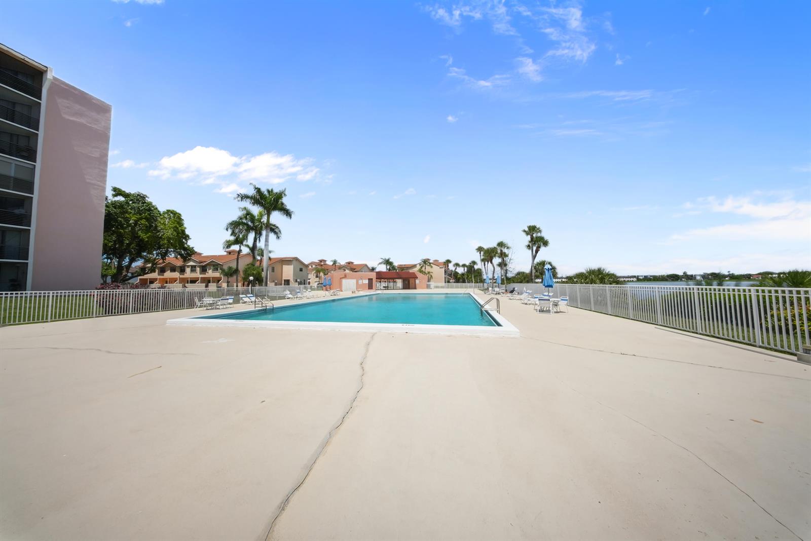 A rectangular swimming pool sits on a concrete deck surrounded by a white fence — 20860 San Simeon Way # 6, Miami FL 33179, MIAMI, FL