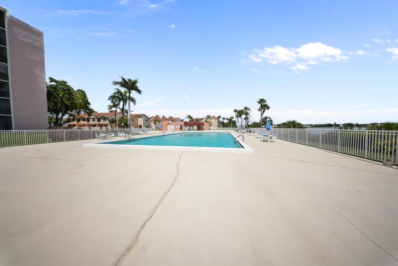 A rectangular outdoor swimming pool is surrounded by a concrete deck and white fencing — 20860 San Simeon Way # 6, Miami FL 33179, MIAMI, FL