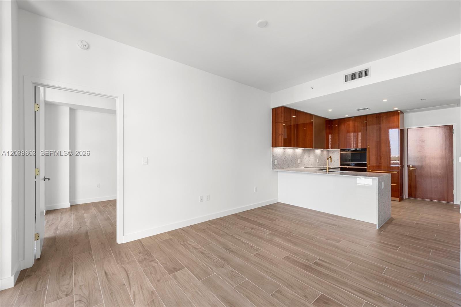 An open-concept living area features wood-look tile flooring and a kitchen with glossy wood cabinets — 2678 Tigertail Ave # 1005, Miami FL 33133, MIAMI, FL