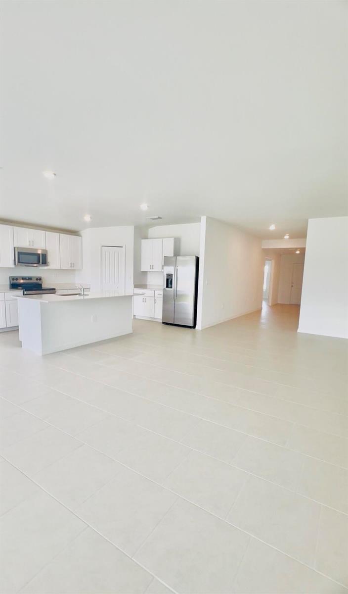 An open-concept kitchen with white cabinets, stainless steel appliances, and a central island — 17124 Pompeii Way, FL 33917, FL