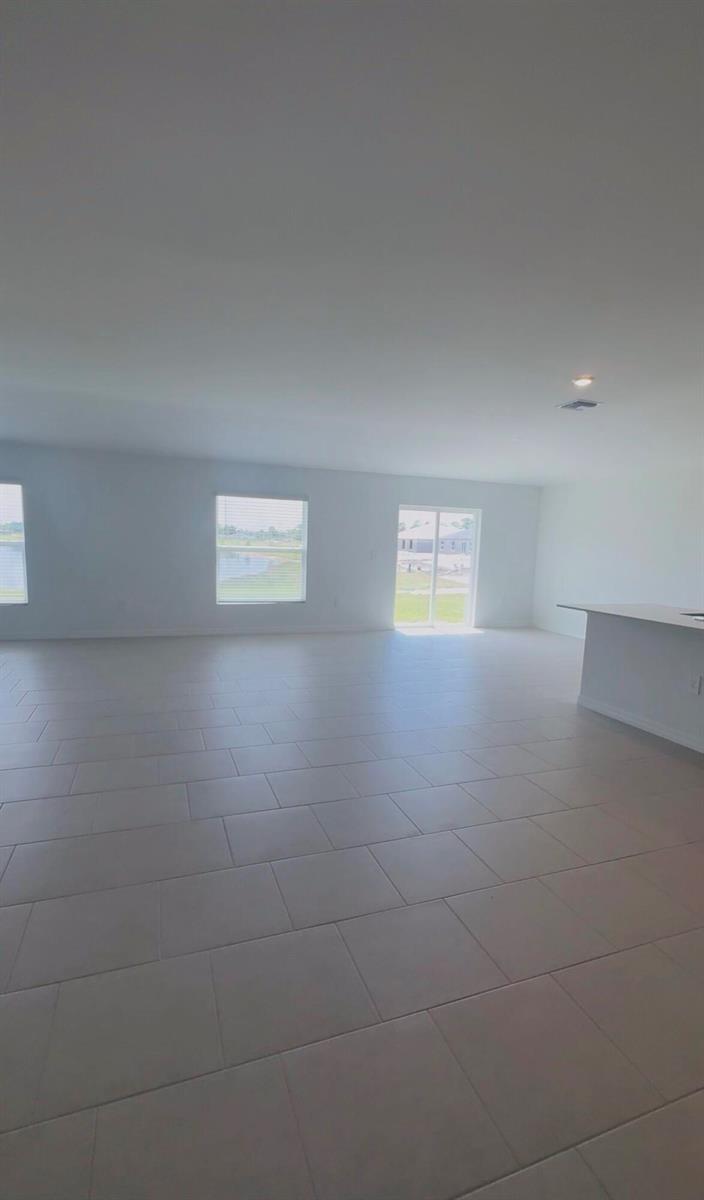 An open-concept living area features light-colored tile flooring, white walls, and sliding glass doors — 17124 Pompeii Way, FL 33917, FL