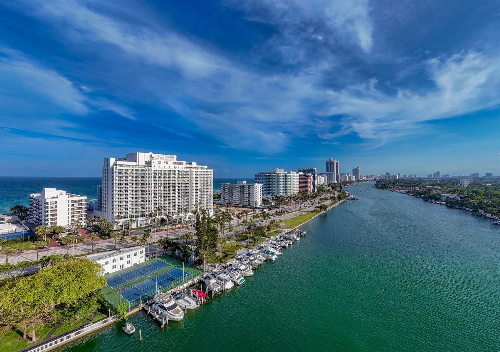 Aerial view of a waterfront high-rise building, tennis courts, and a marina with docked boats — 5401 Collins Avenue # 620, Miami Beach FL 33140, MIAMI BEACH, FL