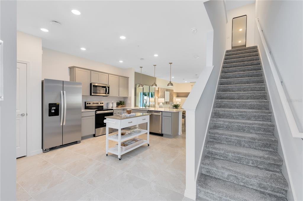 A kitchen with stainless steel appliances and a center island sits beside carpeted stairs — 3113 CANYON BAY POINT, SANFORD, FL