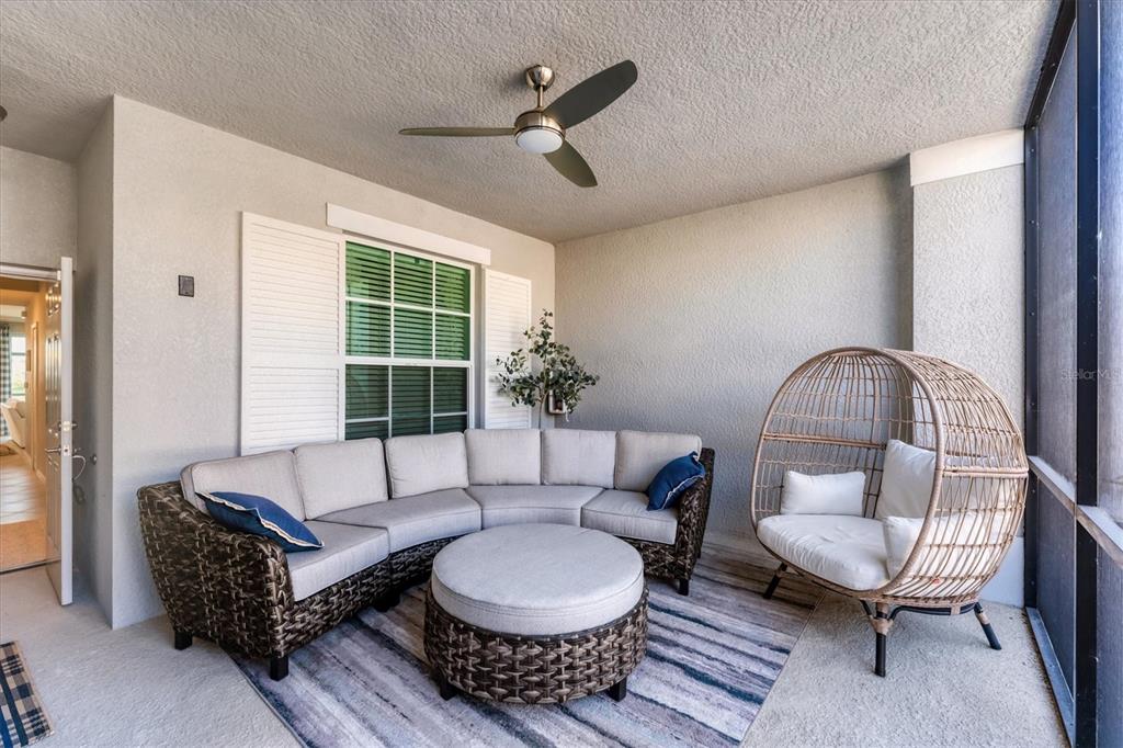A covered patio features a curved wicker sectional, a round ottoman, and a hanging chair — 14184 HERITAGE LANDING BOULEVARD UNIT 516, PUNTA GORDA, FL