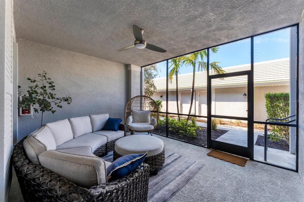 A screened-in patio features a curved sectional sofa, a round ottoman, and a hanging chair — 14184 HERITAGE LANDING BOULEVARD UNIT 516, PUNTA GORDA, FL