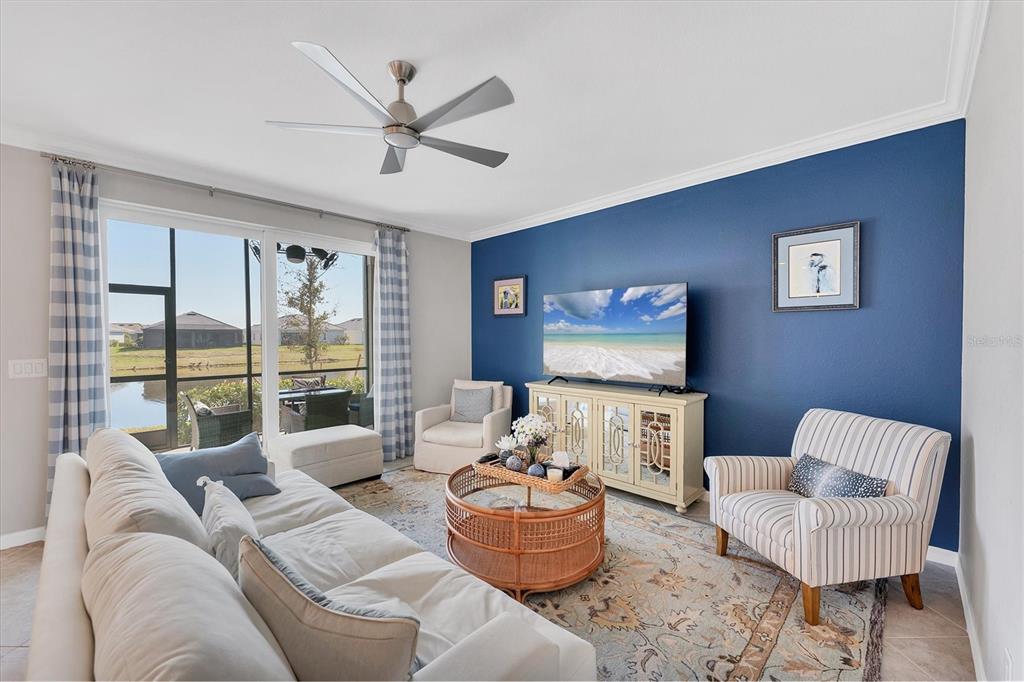 A living room features a blue accent wall, a television, and a view of water — 14184 HERITAGE LANDING BOULEVARD UNIT 516, PUNTA GORDA, FL