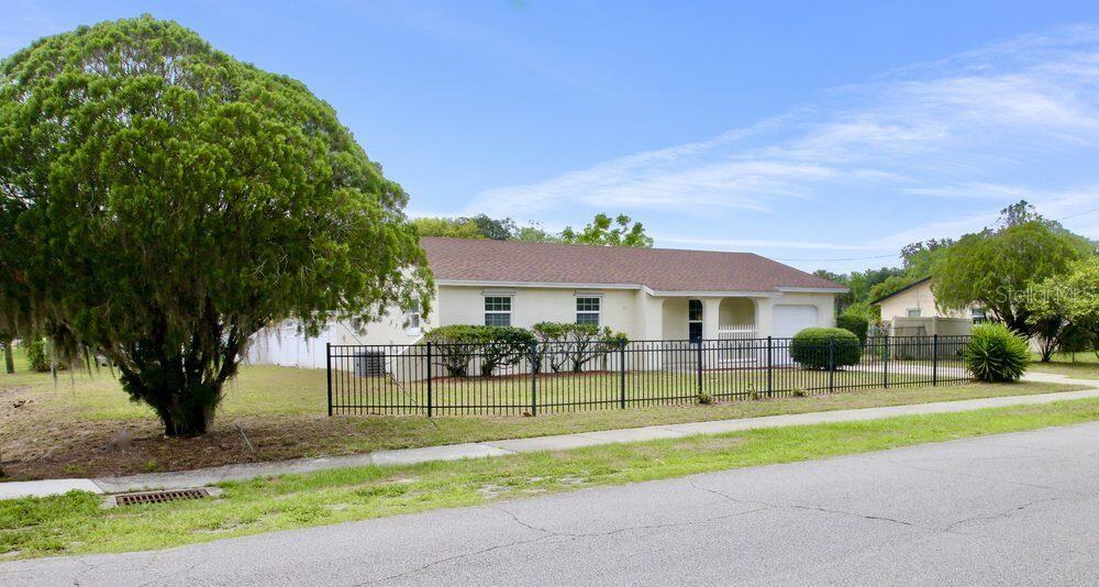 A single-story house with a brown roof and a black metal fence in the yard — 2202 MURDOCK BOULEVARD, ORLANDO, FL