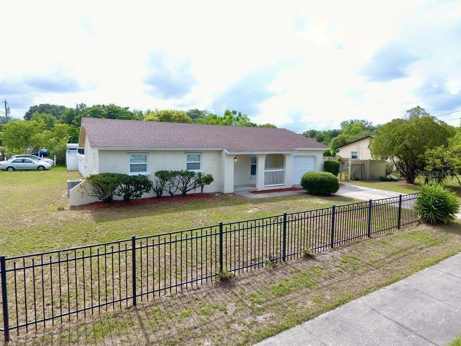 A single-story house with a light-colored exterior, a brown roof, and a black metal fence — 2202 MURDOCK BOULEVARD, ORLANDO, FL
