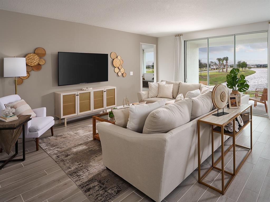 A living room features a beige sectional, a wall-mounted television, and sliding doors overlooking water — 3910 NATURE SOUND LANE, BARTOW, FL