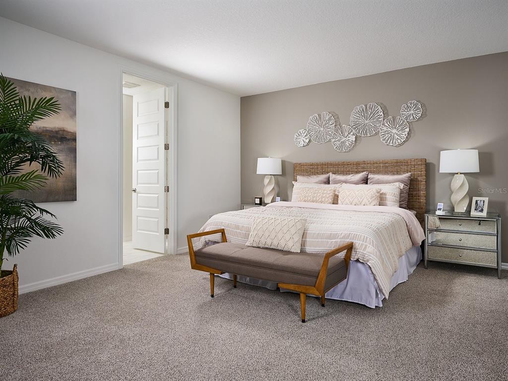 A bedroom features a bed with a woven headboard, a bench, and wall-mounted floral decor — 3910 NATURE SOUND LANE, BARTOW, FL
