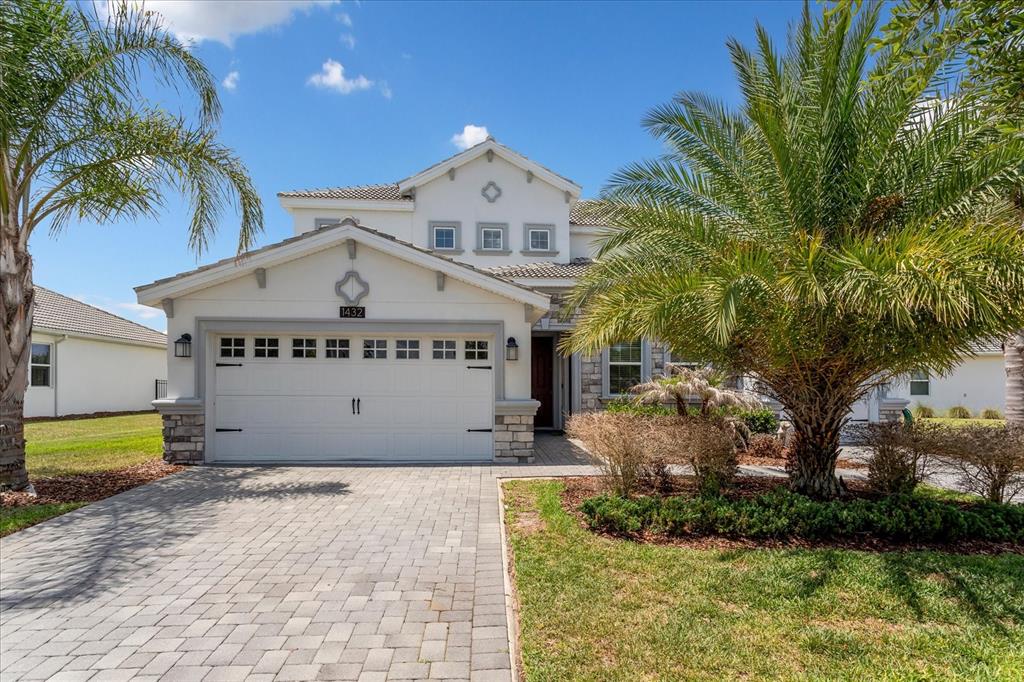 A two-story house with a white stucco facade, stone accents, and a paved driveway — 1432 OLYMPIC CLUB BOULEVARD, CHAMPIONS GATE, FL