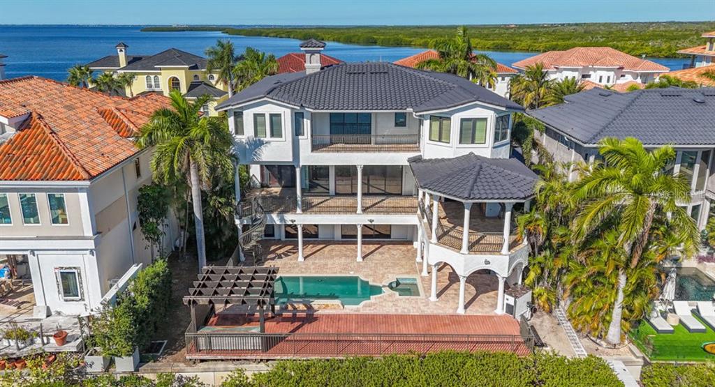 An aerial view of a three-story waterfront home with a pool, pergola, and tiled roof — 4107 CAUSEWAY VISTA DRIVE, TAMPA, FL