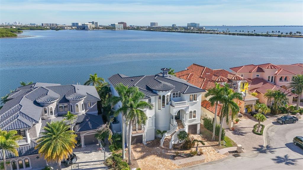 An aerial view shows three multi-story waterfront homes with tiled roofs and palm trees — 4107 CAUSEWAY VISTA DRIVE, TAMPA, FL