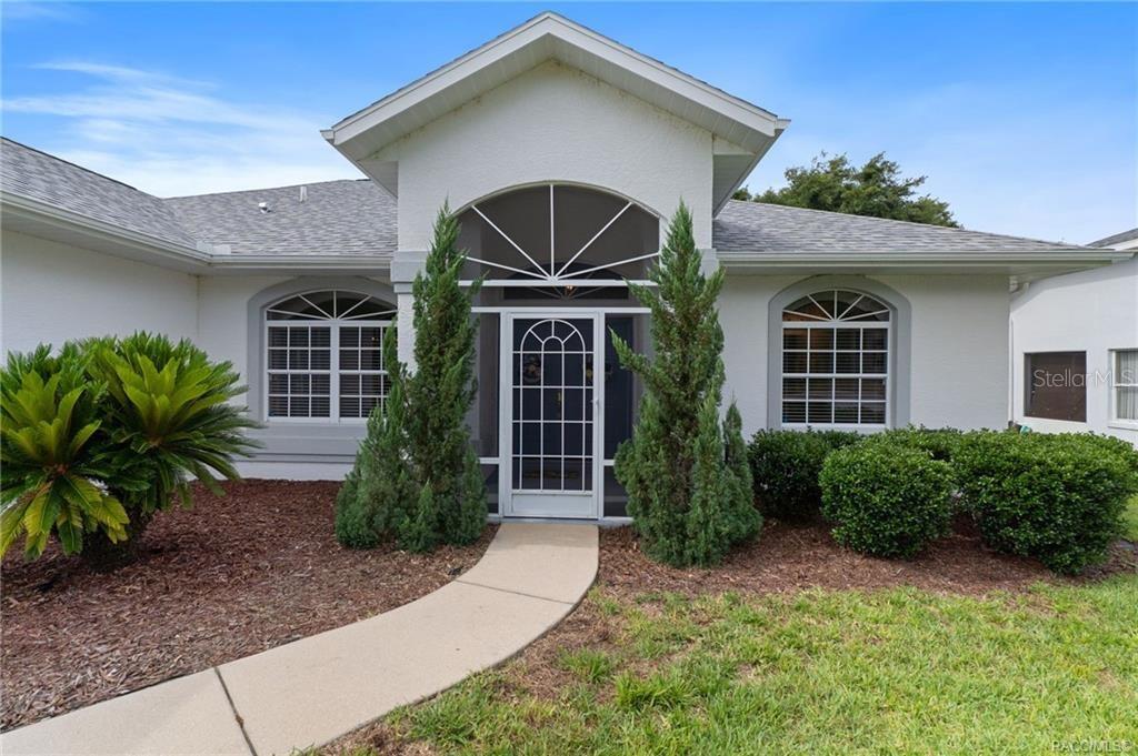 The exterior of a white house features a covered entryway with a screen door — 2786 N CANTERBURY LAKE DRIVE, HERNANDO, FL