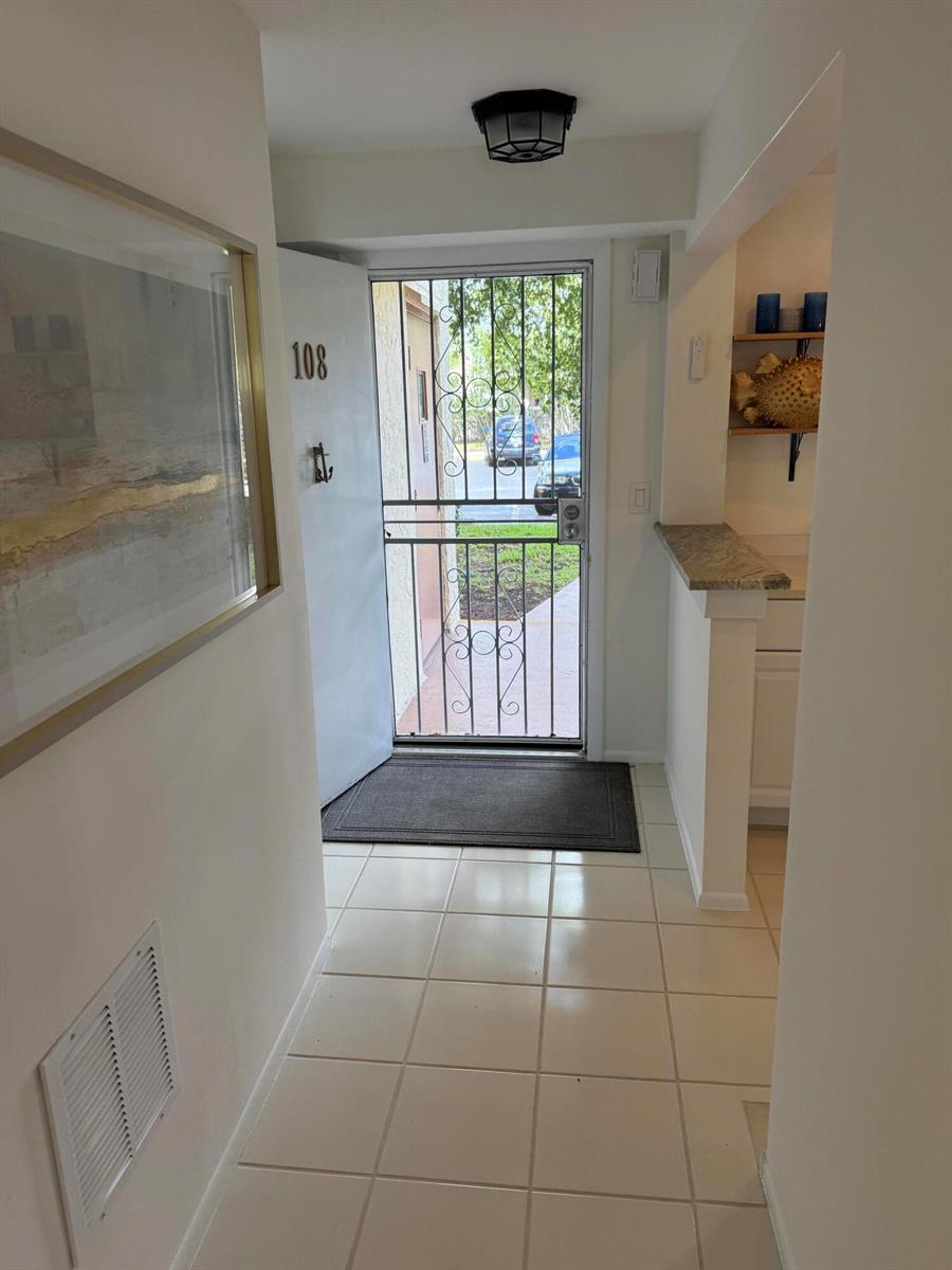 An entryway with tiled floors, a security screen door, and a partial wall with shelving — 111 SE 3rd Avenue # 108, Dania Beach FL 33004, DANIA BEACH, FL