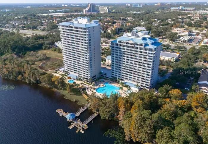 An aerial view shows two high-rise residential buildings next to a lake and pool — 13415 BLUE HERON BEACH DRIVE UNIT 1102, ORLANDO, FL