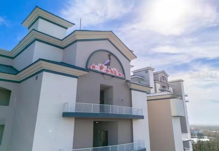 An exterior view of a multi-story building featuring a decorative heron and flower mural — 13415 BLUE HERON BEACH DRIVE UNIT 1102, ORLANDO, FL