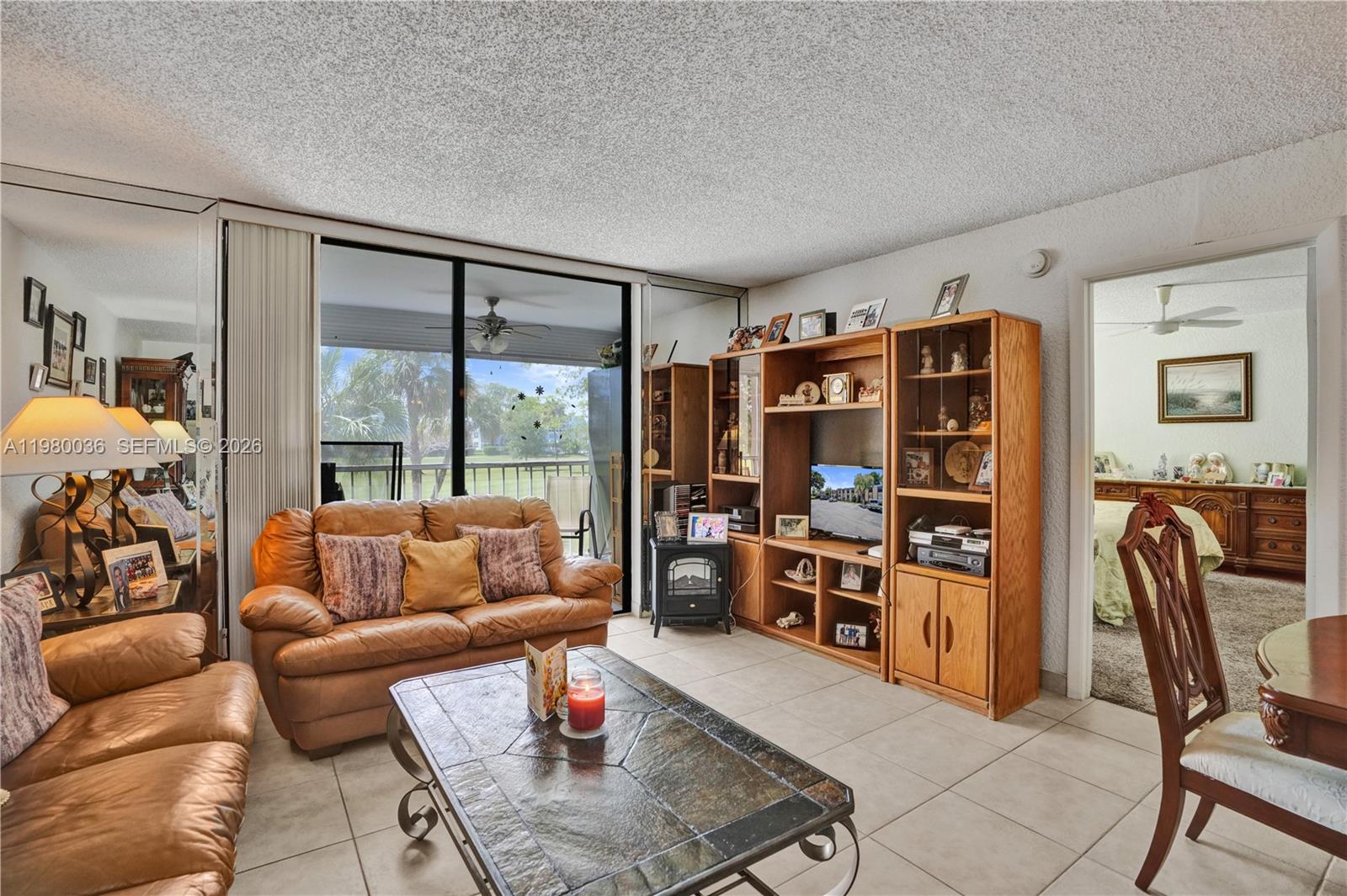 A living room features a leather sofa, a tiled floor, and a large wooden entertainment center — 7400 NW 18th St # 204, Margate FL 33063, MARGATE, FL