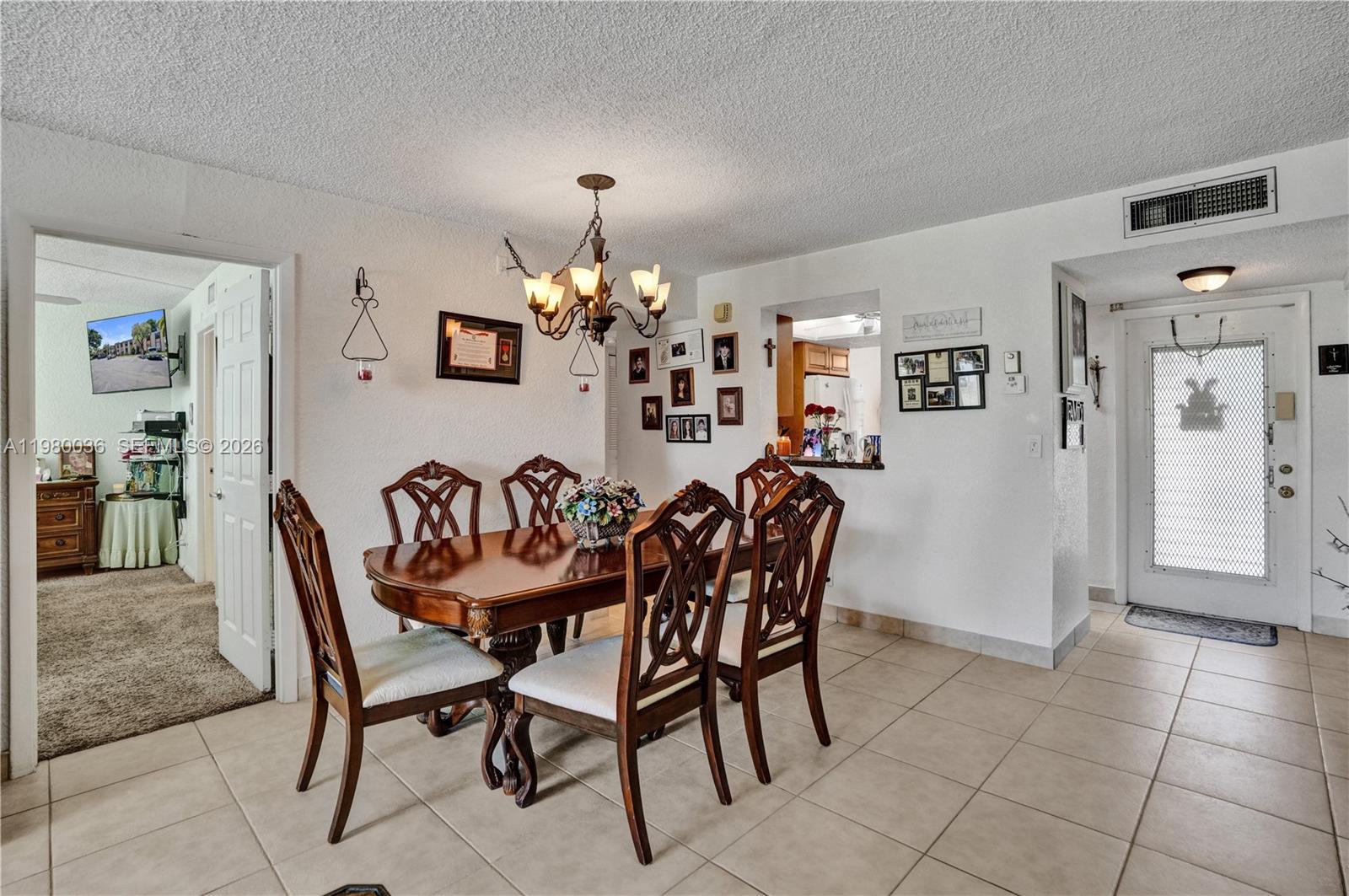 A dining room features a wooden table, six chairs, a chandelier, and tiled flooring — 7400 NW 18th St # 204, Margate FL 33063, MARGATE, FL