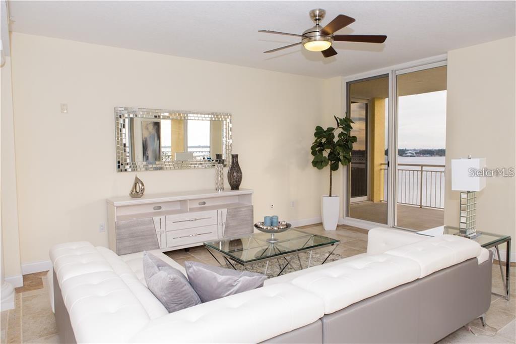 A living room features a white sectional sofa, a glass coffee table, and a balcony view — 611 RIVIERA DUNES WAY UNIT 604, PALMETTO, FL