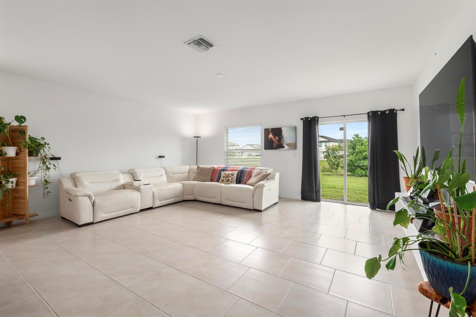 A living room features white walls, tile flooring, a large sectional sofa, and sliding glass doors — 17177 Monte Isola Way, FL 33917, FL