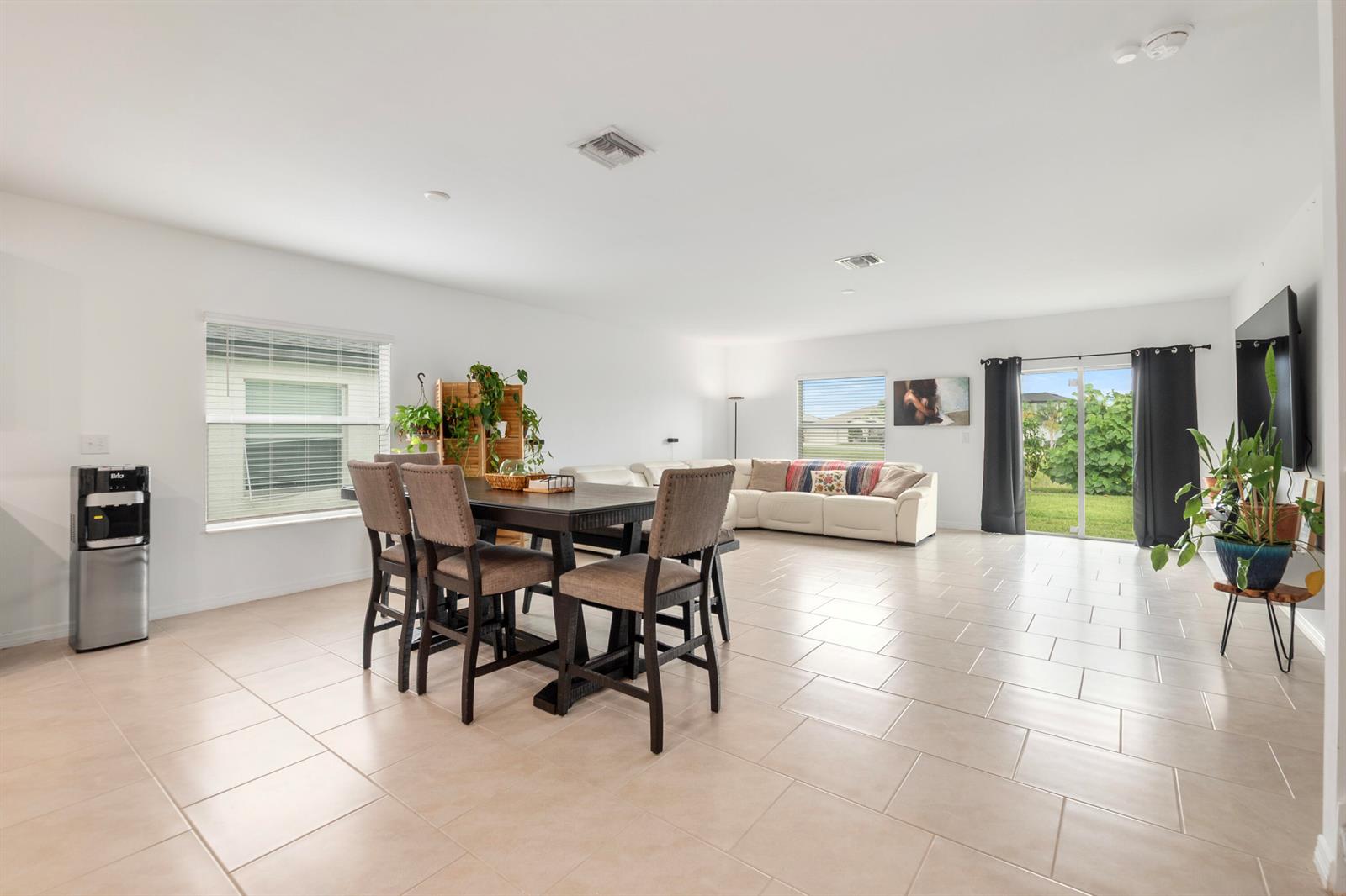 An open-concept living and dining area features tile flooring, a sectional sofa, and sliding doors — 17177 Monte Isola Way, FL 33917, FL