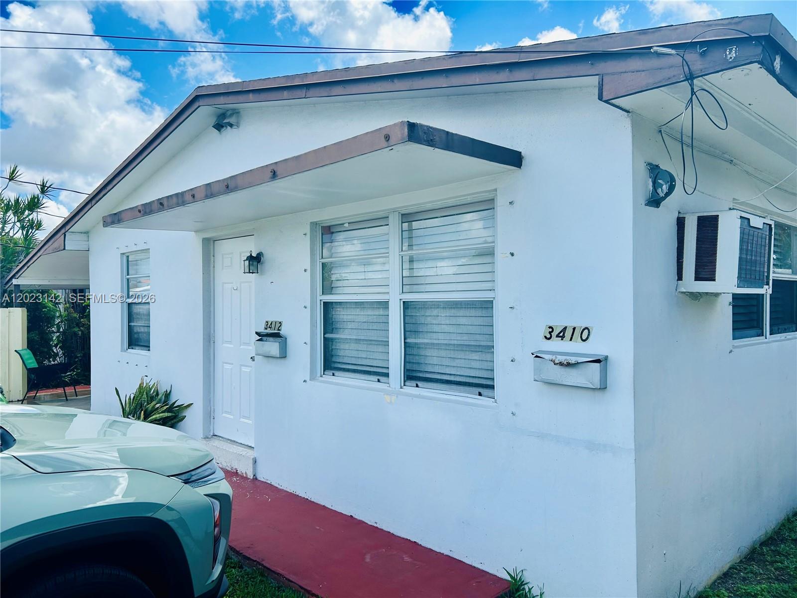 A white exterior of a duplex building features two mailboxes and a window air conditioner — 3410 SW 89th Ct, Miami FL 33165, MIAMI, FL