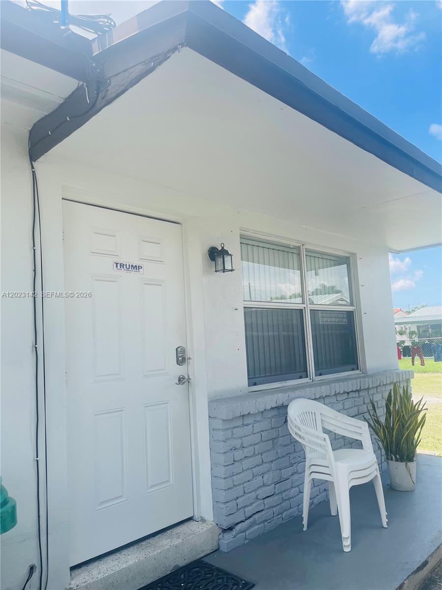 A white exterior door with a political sticker sits beside a window and white chair — 3410 SW 89th Ct, Miami FL 33165, MIAMI, FL