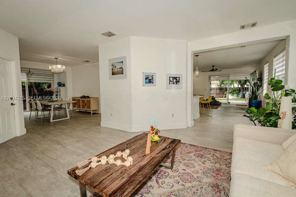 This open-concept living area features light tile flooring, a wooden coffee table, and dining space — 8526 NW 110th Pl # 0, Doral FL 33178, DORAL, FL