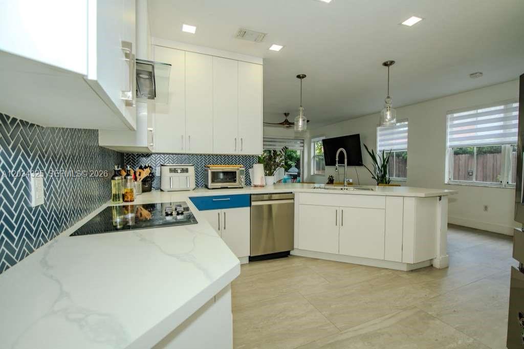 A modern kitchen features white cabinets, quartz countertops, a blue-tiled backsplash, and stainless steel appliances — 8526 NW 110th Pl # 0, Doral FL 33178, DORAL, FL