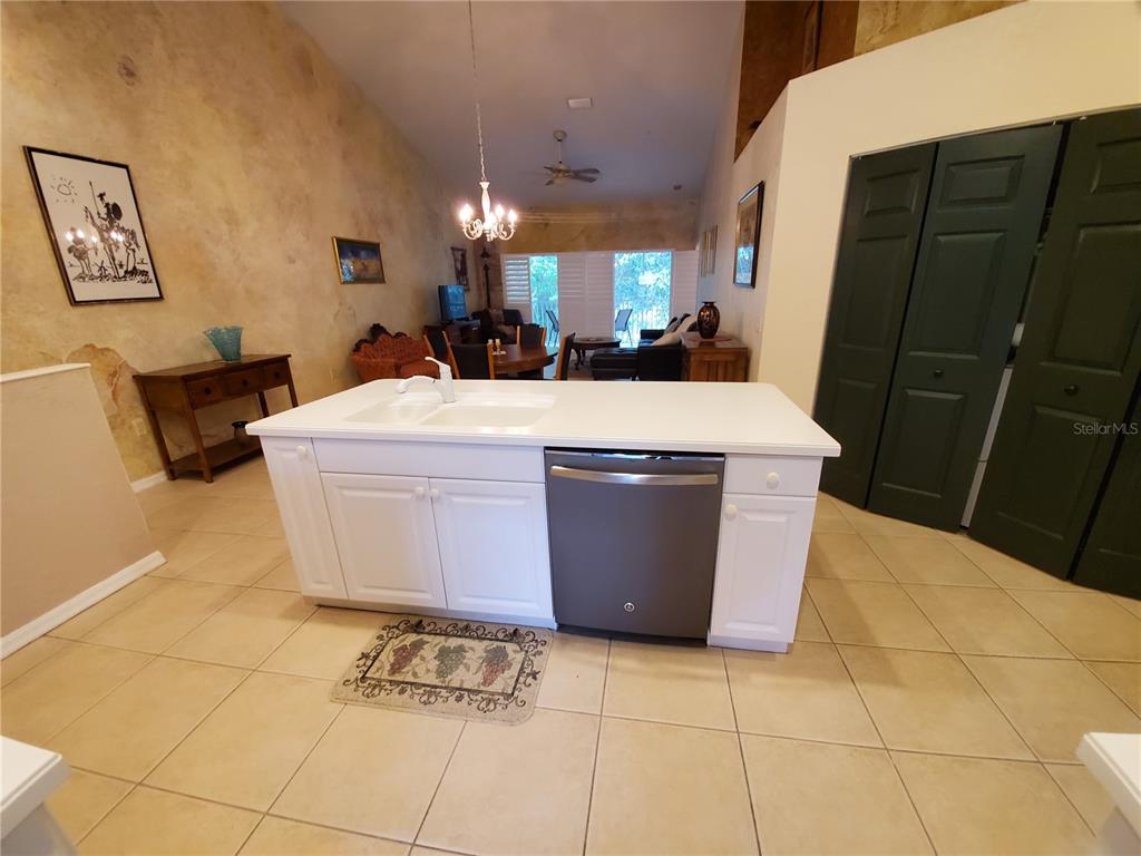 A white kitchen island with a dishwasher sits in a room with tile flooring — 7138 CEDAR HOLLOW CIRCLE, BRADENTON, FL