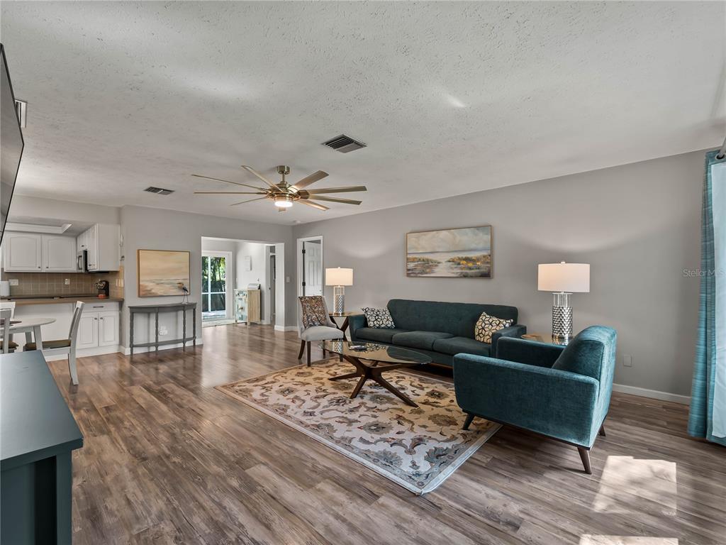 A living room features a teal sofa and armchair, a patterned rug, and wood flooring — 251 PLANTATION ROAD, VENICE, FL