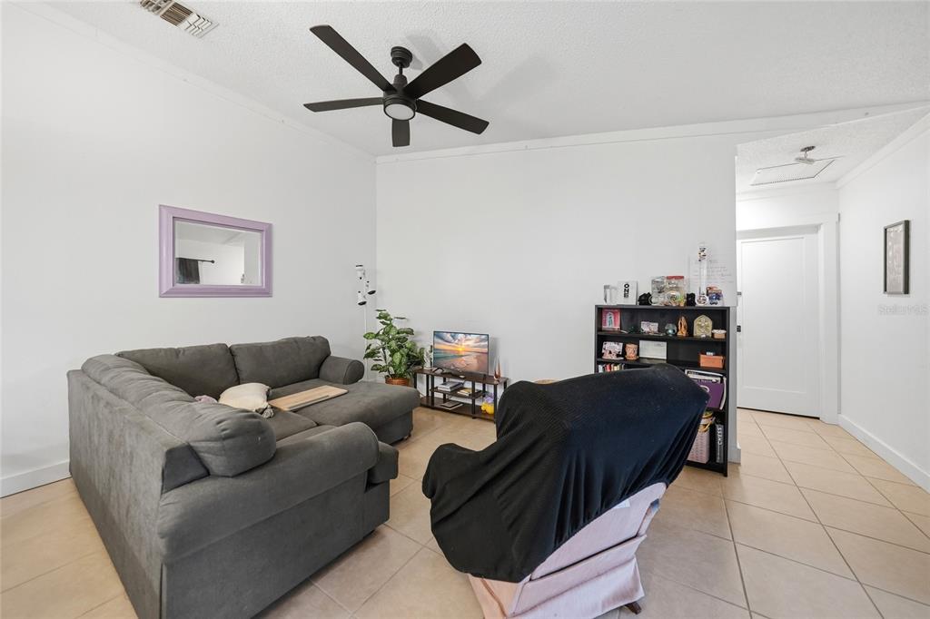 A living room features a gray sectional sofa, a black armchair, and tile flooring — 5625 FOXLAKE DRIVE, NORTH FORT MYERS, FL