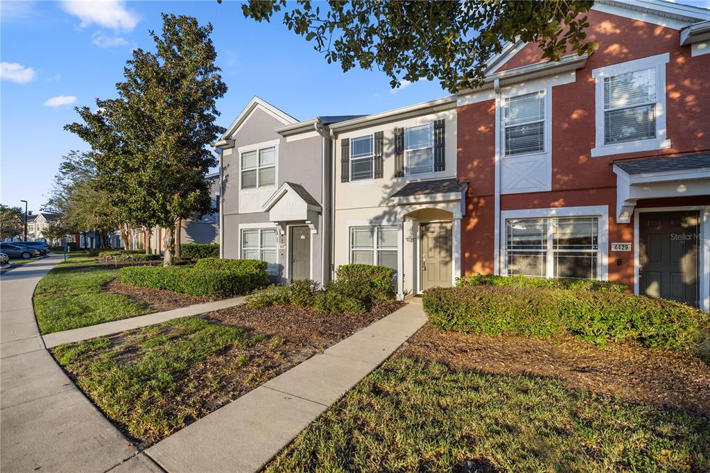 A row of three multi-story townhomes with gray, beige, and red facades and concrete walkways — 4428 SW 49TH AVENUE, OCALA, FL