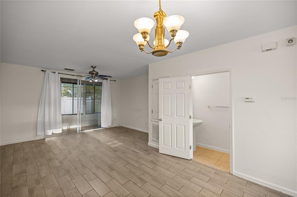 A room with wood-look tile flooring, a ceiling fan, a chandelier, and an open doorway — 4428 SW 49TH AVENUE, OCALA, FL