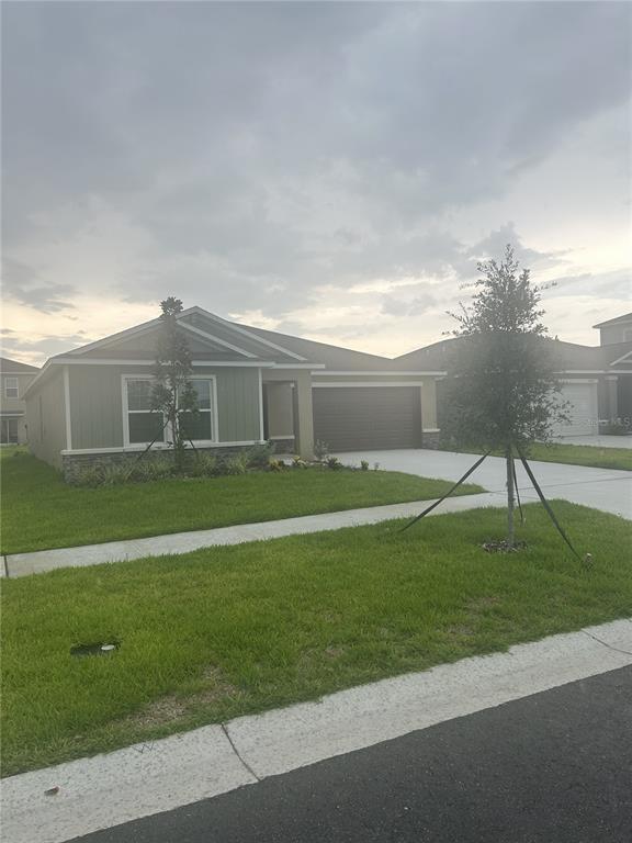 The exterior of a house features a brown front door, a garage, and stone accents — 15005 EMERSON FIELD STREET, WIMAUMA, FL
