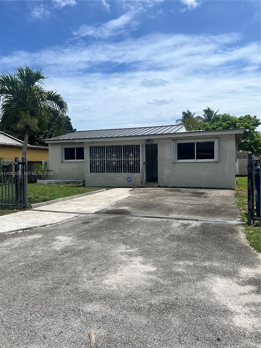 A single-story house with a metal roof, security bars on windows, and a concrete driveway — 250 NE 160th St, Miami FL 33162, MIAMI, FL