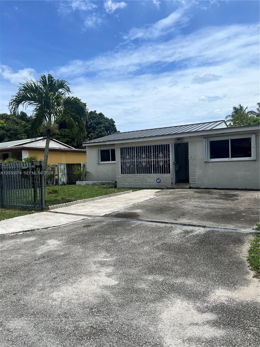 A single-story house with a metal roof, a paved driveway, and security bars on windows — 250 NE 160th St, Miami FL 33162, MIAMI, FL