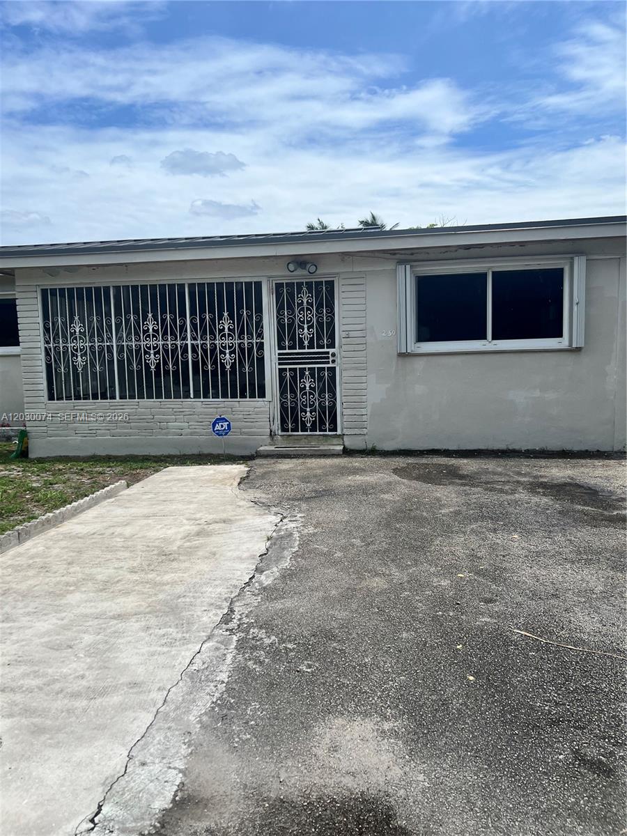 The exterior of a single-story house features a concrete driveway, security bars, and an entrance — 250 NE 160th St, Miami FL 33162, MIAMI, FL