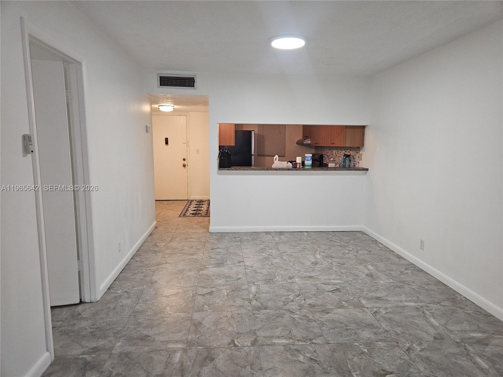 A room with gray tile flooring features a pass-through window looking into a kitchen — 7610 Stirling Rd # 102C, Davie FL 33024, DAVIE, FL