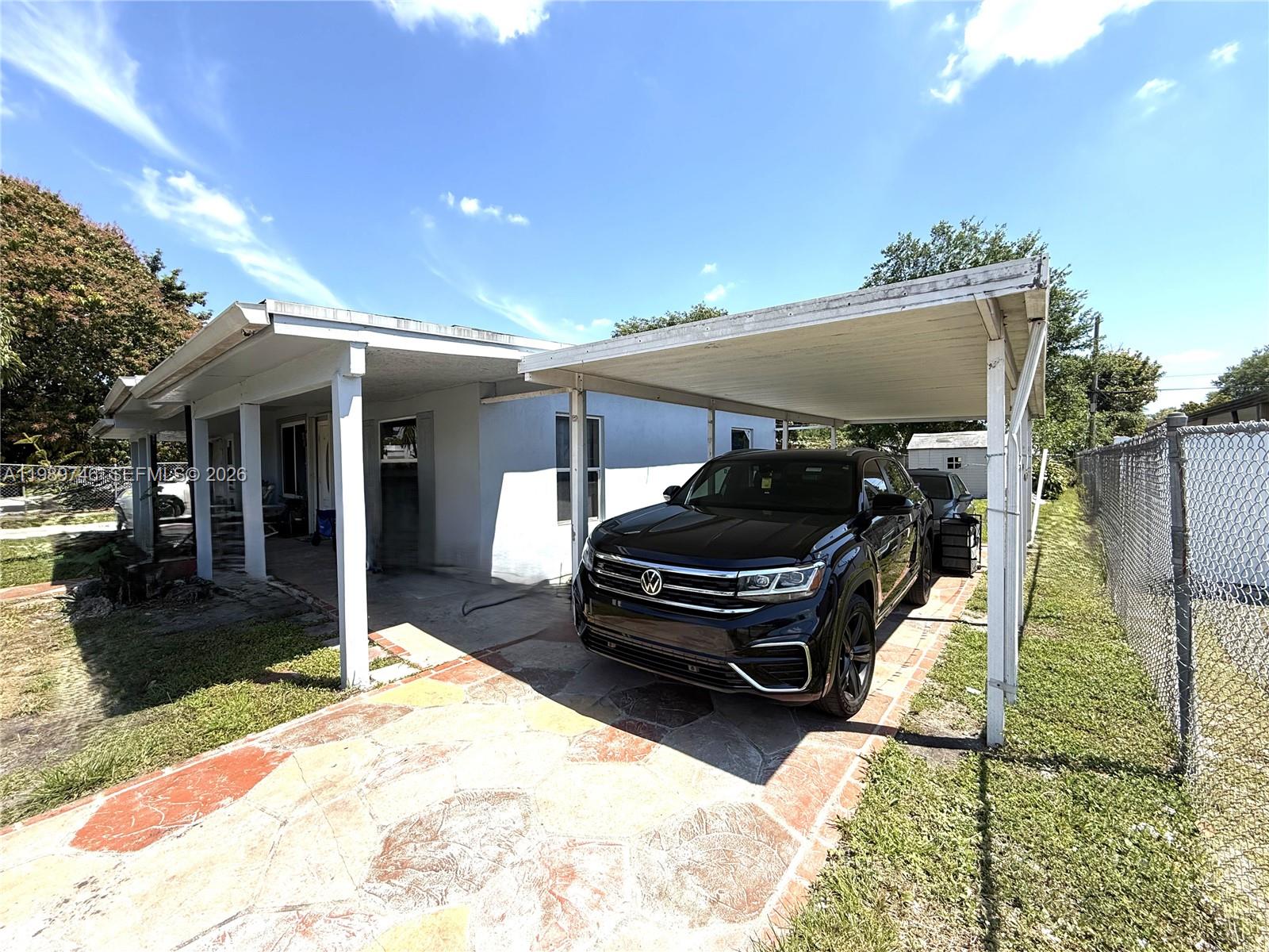 A black SUV is parked under a carport attached to the side of a house — 9615 NW 26th Ave, Miami FL 33147, MIAMI, FL