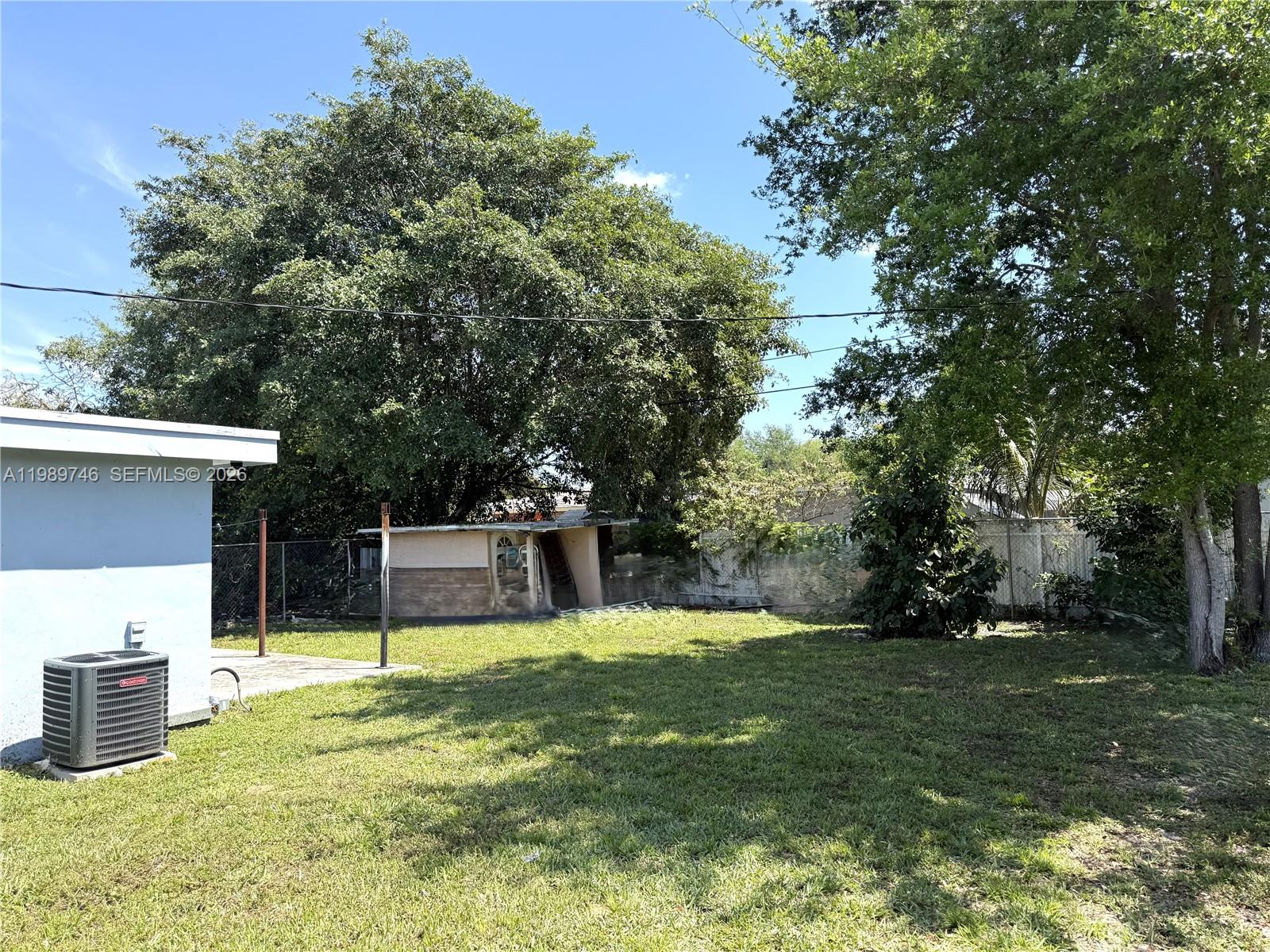 A grassy backyard features a small shed, a central air conditioning unit, and mature trees — 9615 NW 26th Ave, Miami FL 33147, MIAMI, FL