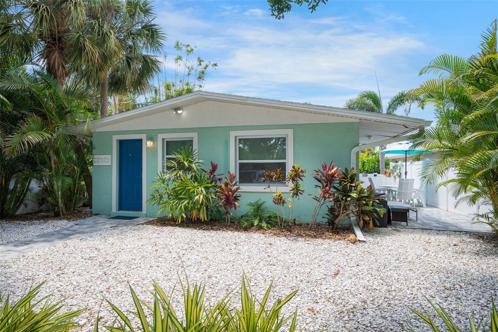 A light green cottage with a blue door sits behind a white gravel yard — 2053 ROSELAWN STREET, SARASOTA, FL