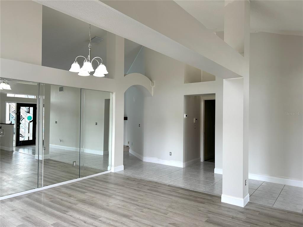 A living area features light wood-look flooring, mirrored walls, and a white chandelier — 11417 GLENMONT DRIVE, TAMPA, FL