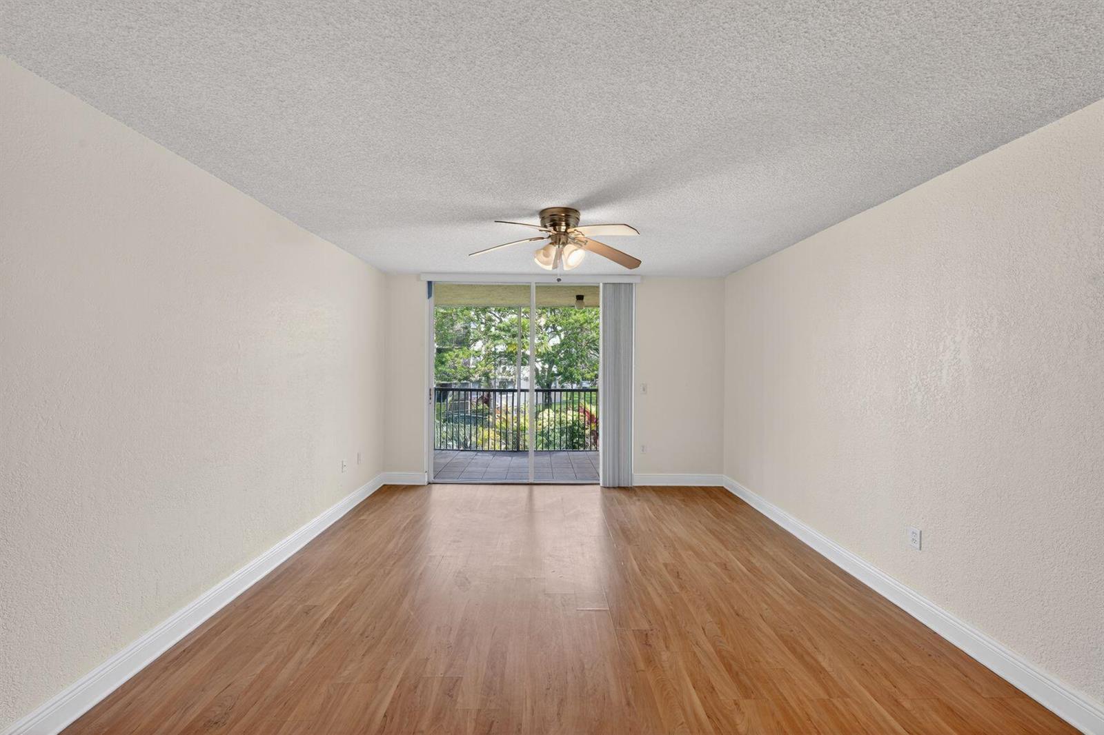 An empty room with wood-look flooring, a ceiling fan, and a sliding door to a balcony — 8353 Lake Drive # 204, Doral FL 33166, DORAL, FL