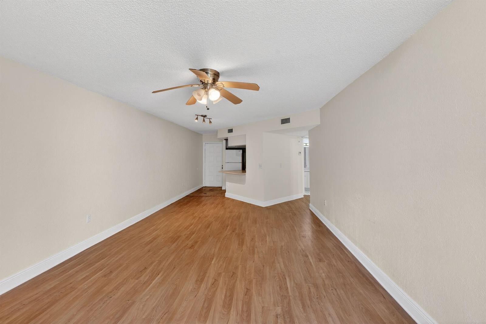 An empty room with light wood-look flooring, beige walls, and a ceiling fan — 8353 Lake Drive # 204, Doral FL 33166, DORAL, FL