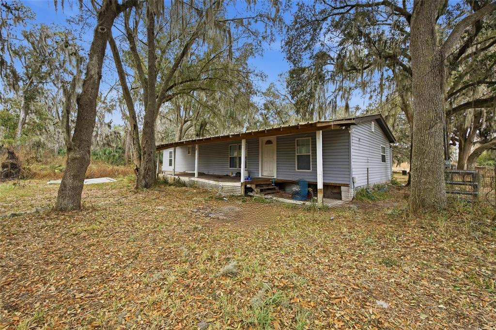 A single-story house with light blue siding and a covered front porch among trees — 1823 WELCOME ROAD, LITHIA, FL