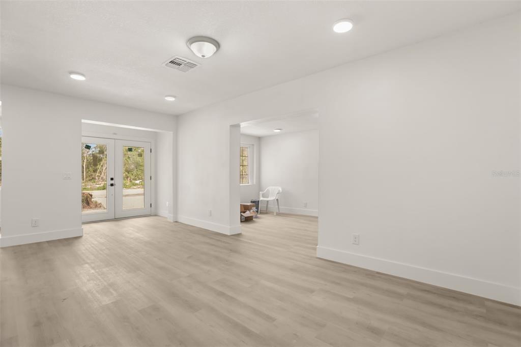 An interior view of a room with light wood-look flooring and double glass doors — 127 LEON STREET, ALTAMONTE SPRINGS, FL