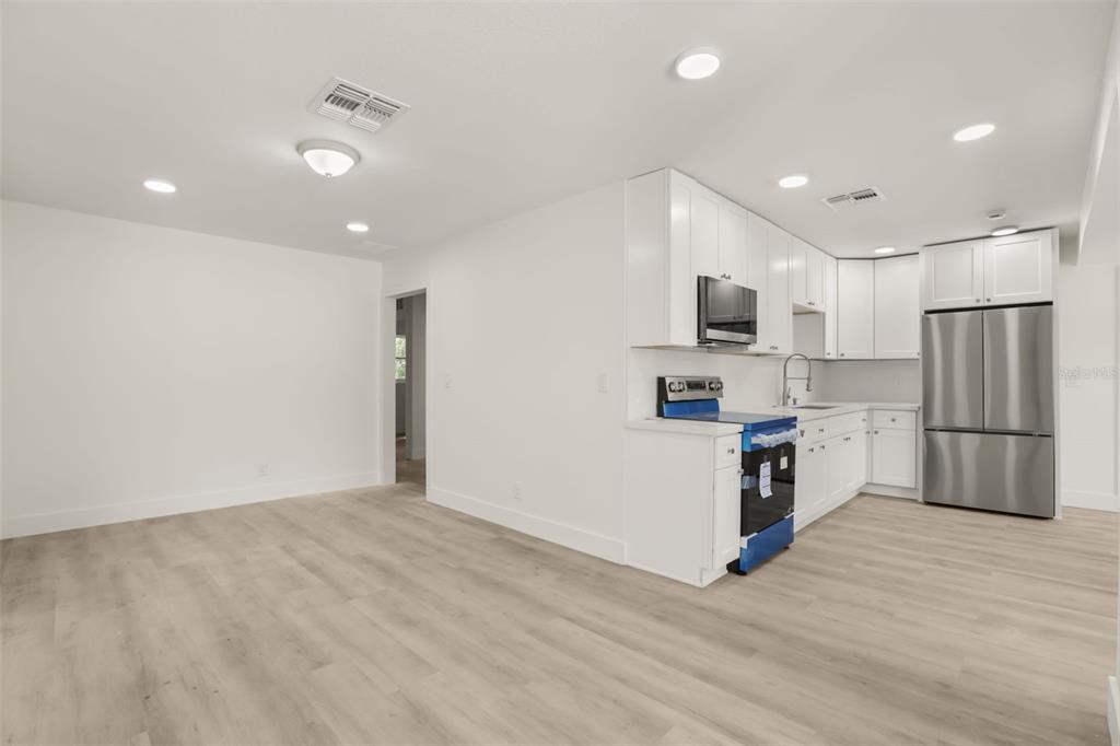 A bright kitchen features white cabinets, stainless steel appliances, and light wood-look flooring — 127 LEON STREET, ALTAMONTE SPRINGS, FL
